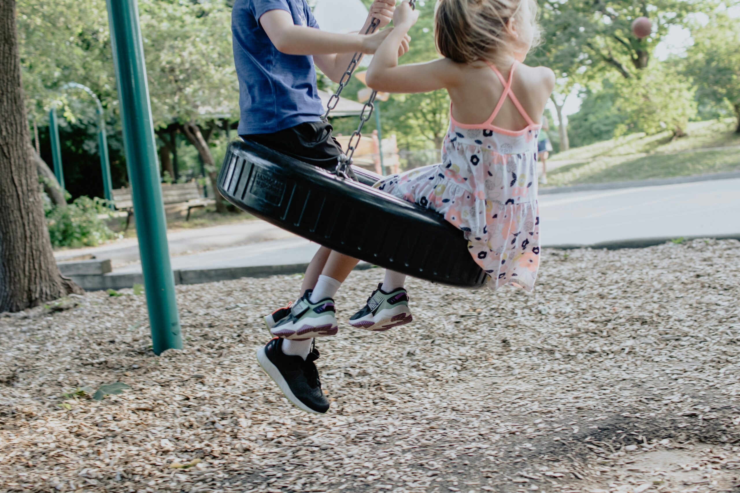 Zwei Kinder schaukeln auf einem Spielplatz.