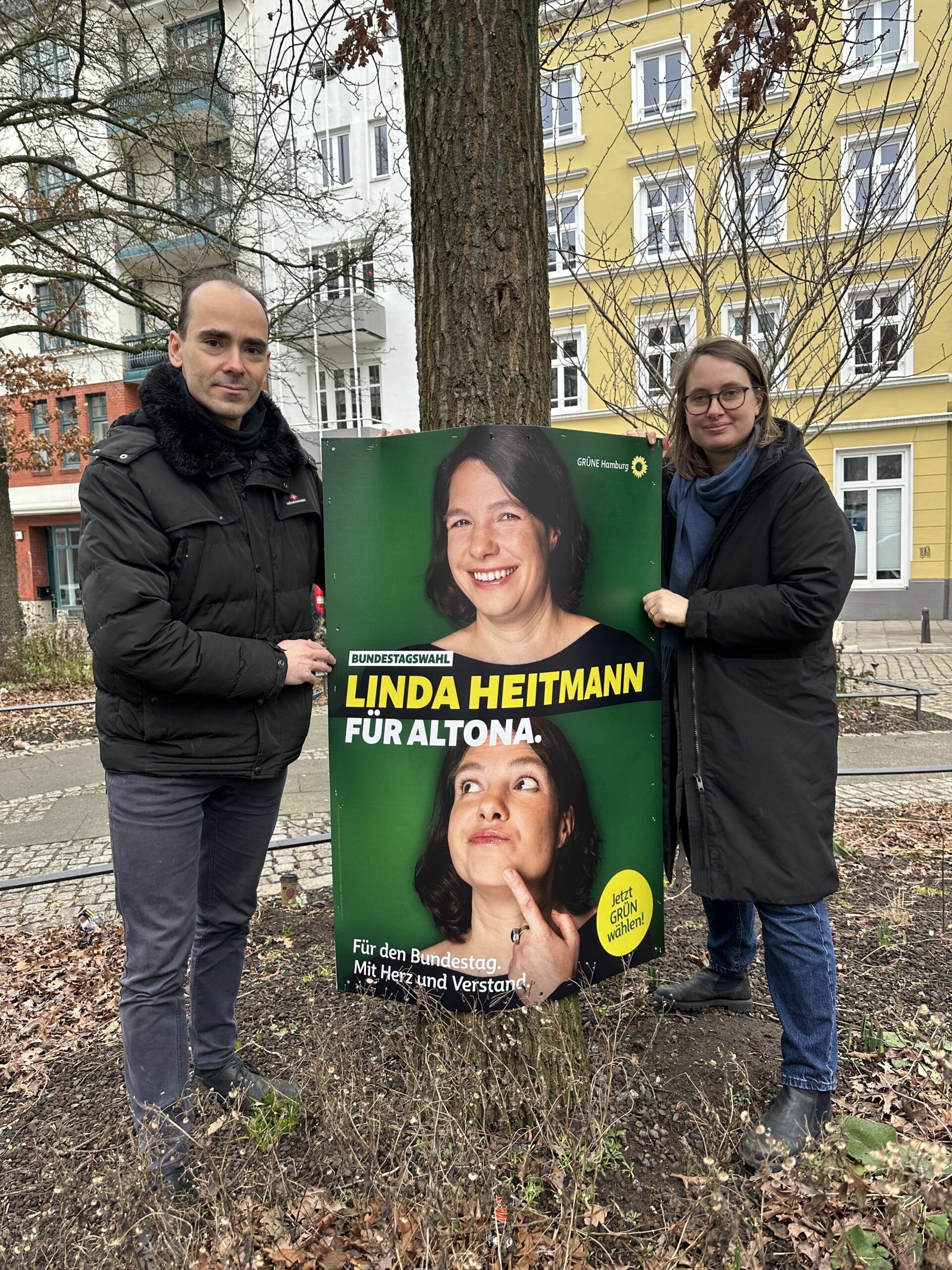 Banjamin Harders und Mareike Engels stehen an einem Plakat von Linda Heitmann.