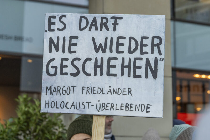 Demoschild mit dem Zitat von Margot Friedländer "Es darf nie wieder geschehen" 