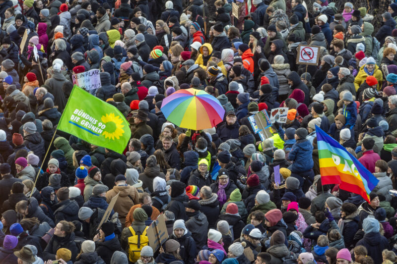 Zoom auf die Demo gegen die AFD im Januar 2024 am Jungfernstieg mit Fahne der GRÜNEN und Regenbogenflaggen