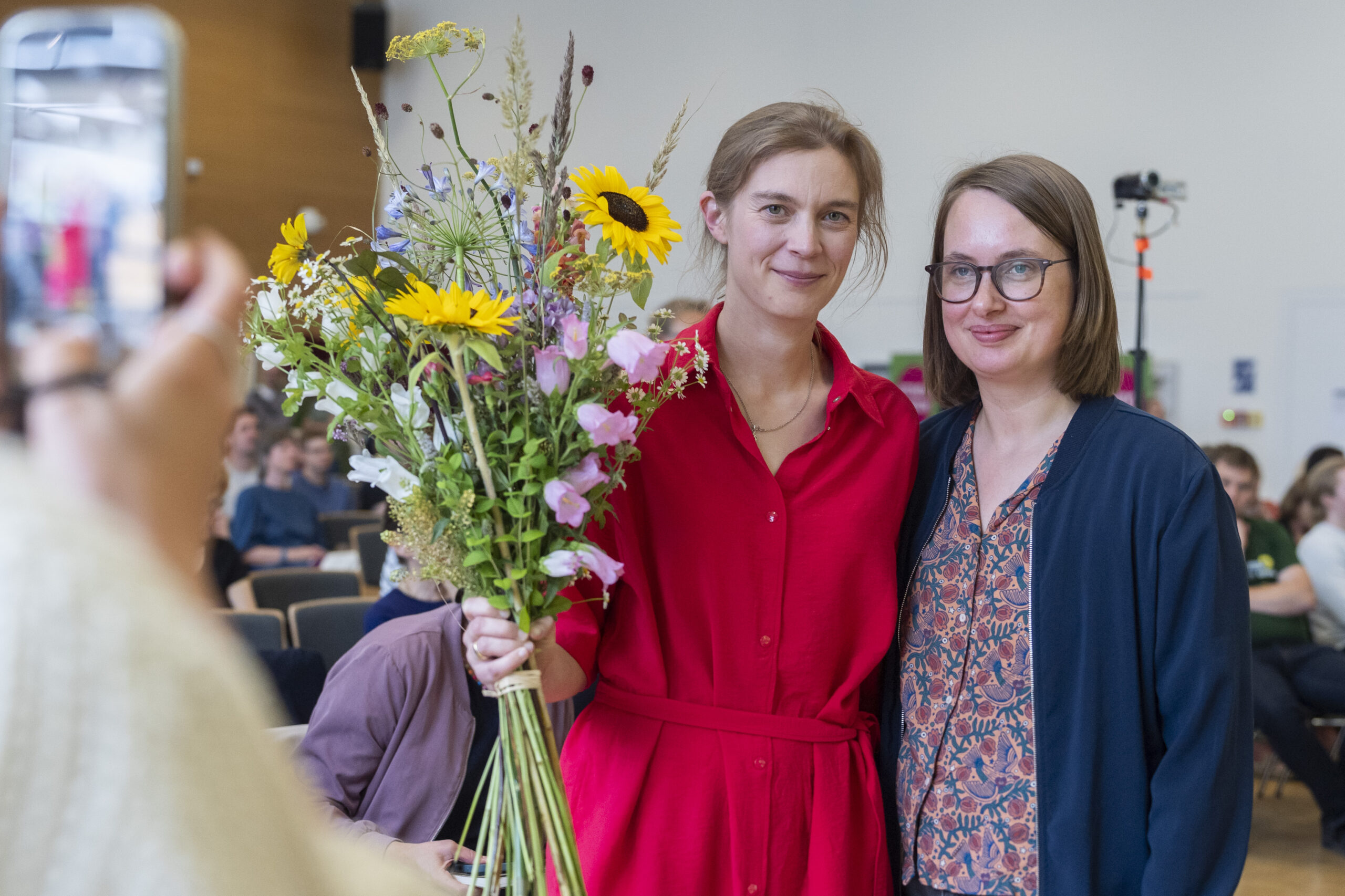 Selina Storm mit großem Blumenstrauß in der Hand wird von Mareike Engels zur Wahl zur Landesvorsitzenden beglückwünscht.