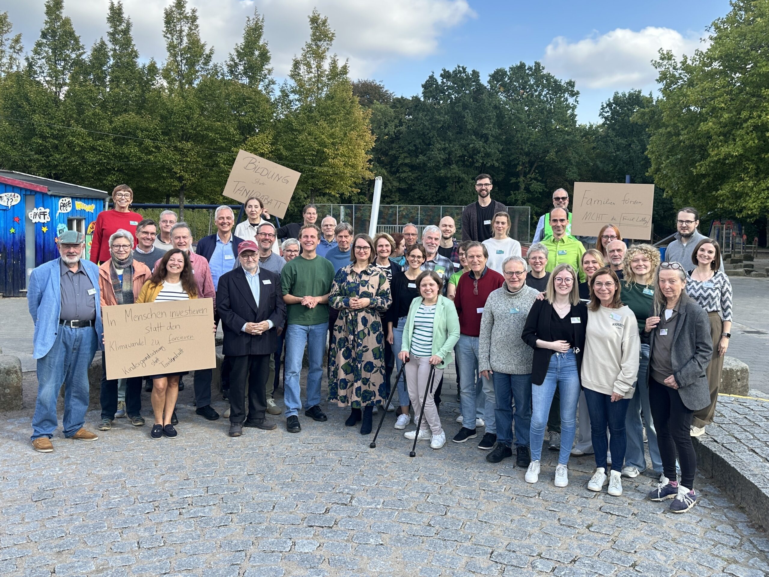 Die gesamte Versammlung steht zusammen als Gruppe und hält Demoschilder hoch für einen starken Sozialstaat.